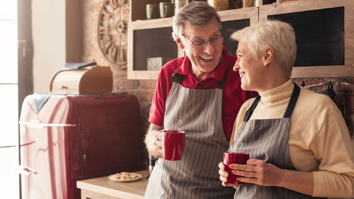 Senior man and woman having nice morning talk with coffee in kitchen