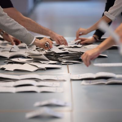 Wahlhelfer:innen zählen in einem Wahllokal Stimmzettel.
