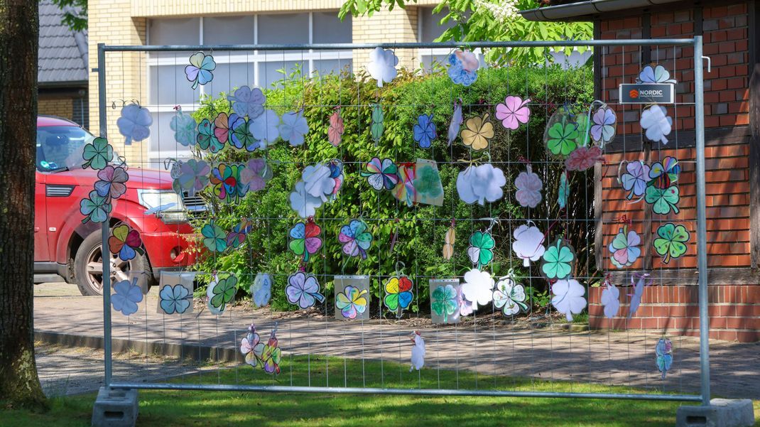 Gebastelte Kleeblätter mit Wünschen für den vermissten Arian hängen vor dem Bürgerhaus an einem Zaun. 
