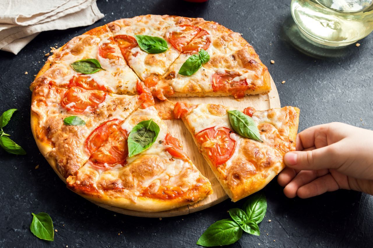 Die Pizza Margherita präsentiert sich in den italienischen Nationalfarben: mit roten Tomaten, weißem Mozzarella und grünem Basilikum. Der Käse ist durch seinen hohen Fett-Gehalt ein perfekter Geschmacksträger. 150 bis 200 Gramm Mozzarella reichen zum Belegen, da die Pizza sonst matschig wird. Wer Zeit sparen will, verwendet einen Fertig-Teig.