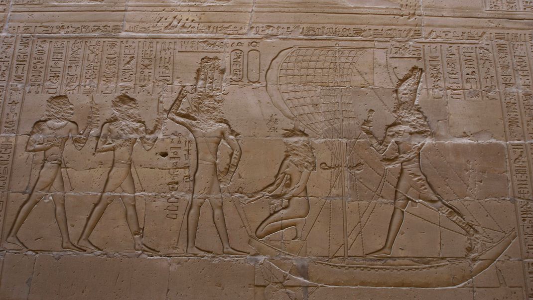 Relief von Horus im Kampf mit Seth (rechts), Horus und Isis (kniend) auf einem Schiff.