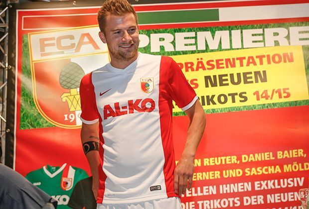 
                <strong>FC Augsburg: Heimtrikot</strong><br>
                Der FC Augsburg hat zu Beginn der Saison 2014/15 den Ausrüster gewechselt. Um so gespannter sind die Fans auf das neue Heimtrikot. Daniel Baier führt es vor.
              