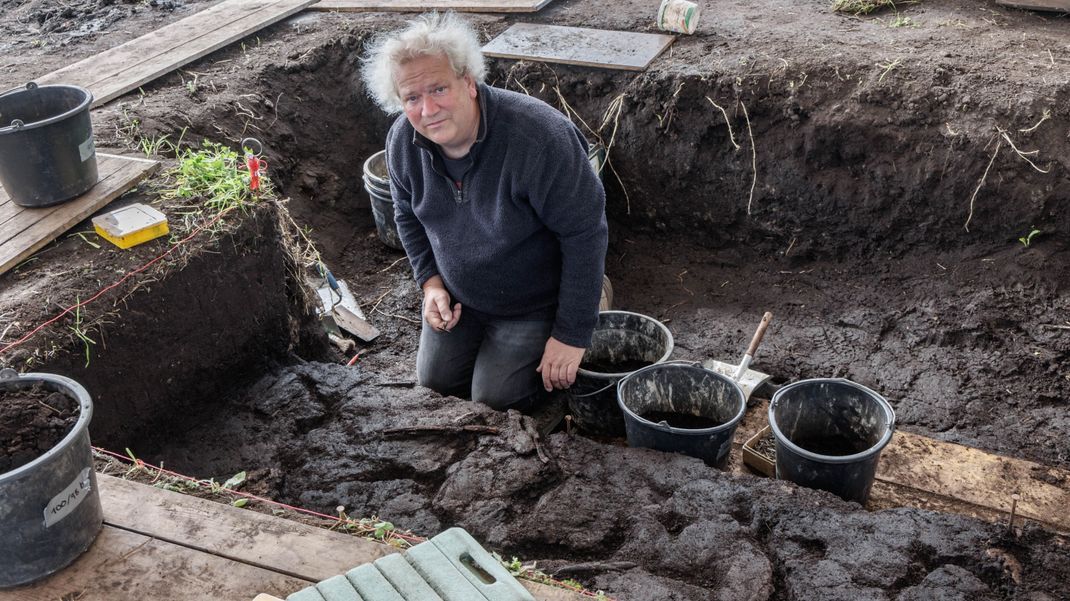 Grabungsleiter Harald Lübke kniet in einem Grabungsschnitt im Duvenseer Moor.