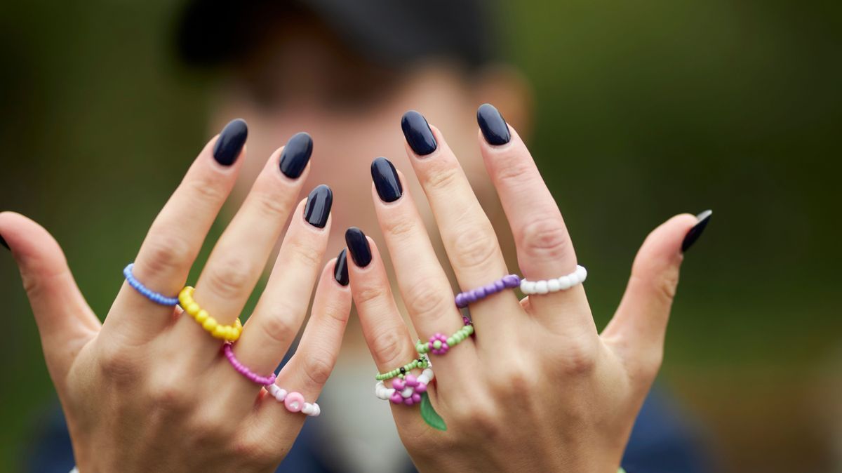 The girl has multi-colored beaded rings on her hands. Woman with manicure on nails. 