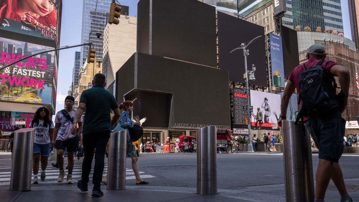 19.07.2024, USA, New York: Fußgänger:innen gehen auf dem Times Square an Bildschirmen vorbei, die aufgrund eines weltweiten Computerausfalls schwarz sind. 