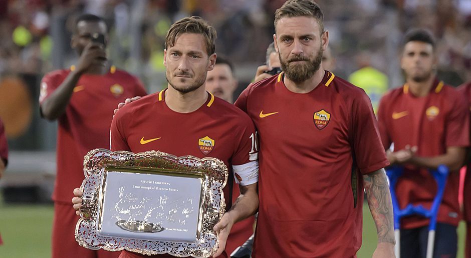 
                <strong>Der tränenreiche Abschied das Francesco Totti</strong><br>
                Als Andenken darf Totti dieses Silberstück in seiner Villa verstauen - übergeben von seinem legitimen Nachfolger Danielle De Rossi. Im Hintergrund hält Antonio Rüdiger die Szene fest.
              