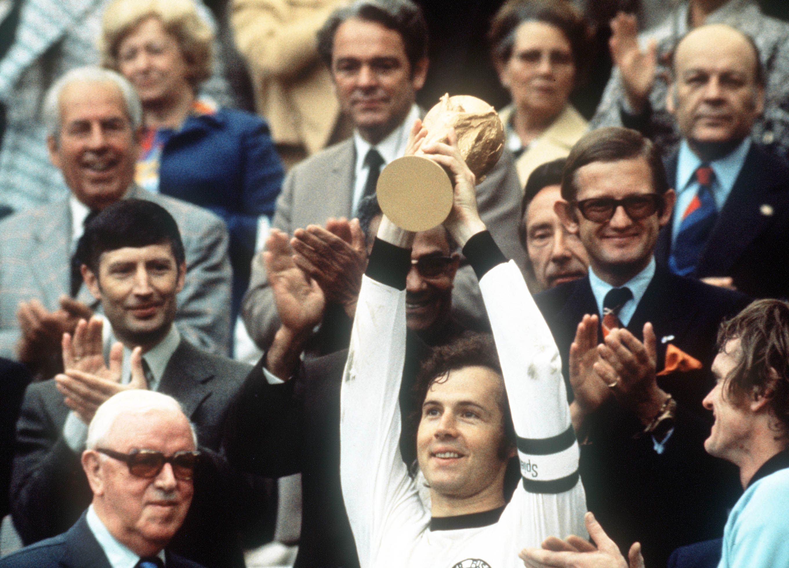 Juli 1974: Kapitän Franz Beckenbauer hebt an der Seite von Torhüter Sepp Maier (rechts) und dem englischen Fifa-Präsidenten Stanley Rous (links) im Olympiastadion nach dem Endspiel der Fußball-WM den eroberten WM-Pokal hoch.