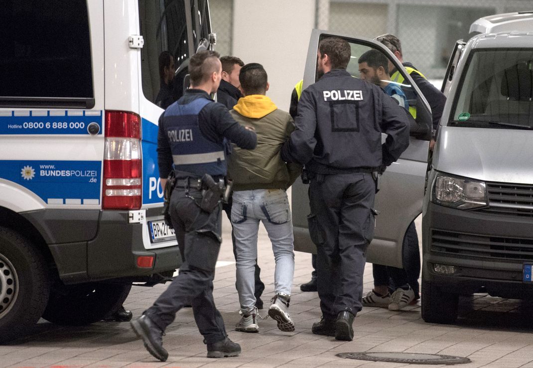 Hand- und Fußfesseln trägt ein junger Mann aus Afghanistan, den Polizisten zur Abschiebung zum Flughafen Frankfurt bringen.