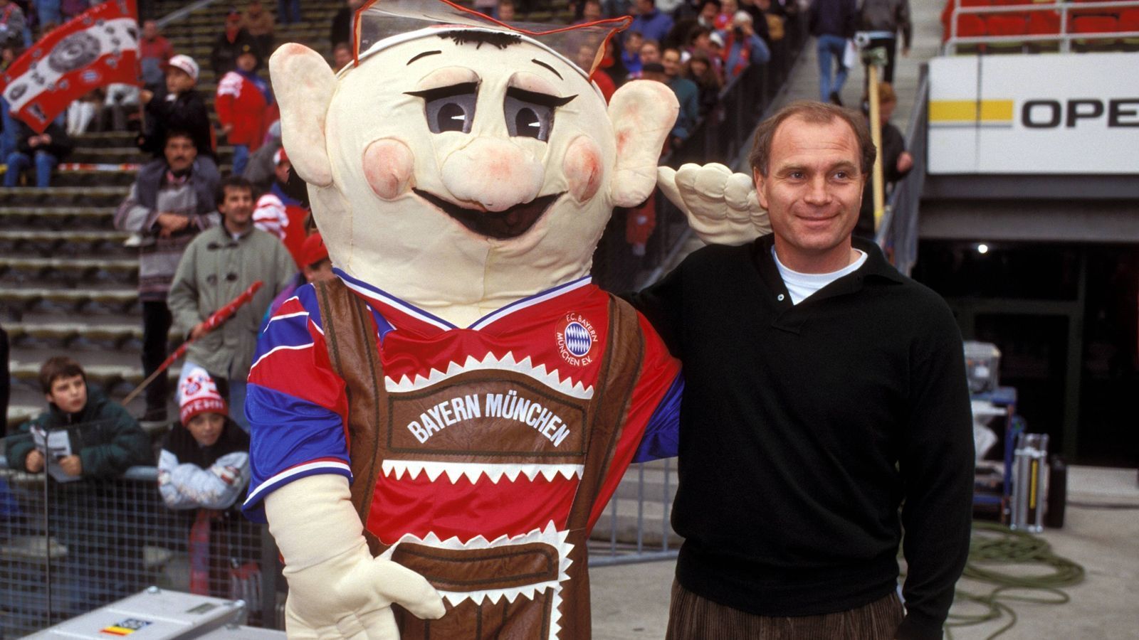 
                <strong>FC Bayern München: Die Maskottchen im Wandel der Zeit</strong><br>
                Zur Saison 1993/94 präsentierte der damalige Bayern-Manager Uli Hoeneß das neue Maskottchen Bazi. Dessen Erscheinungsbild war noch nicht ganz ausgereift und dürfte manches Kind in Alpträumen verfolgt haben.
              