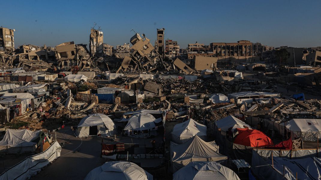 Zelte stehen vor zerstörten Gebäuden im Gazastreifen.