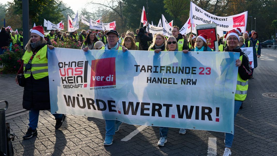 Teilnehmer eines Warnstreiks demonstrieren mit einem Banner mit der Aufschrift "Würde.Wert.Wir!" für die Verdi-Forderungen.