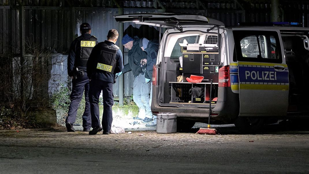 Einsatzkräfte der Polizei untersuchen den Ort einer Explosion außerhalb eines Zauns an einem Polizeigelände in Berlin-Wittenau. Bei der Explosion eines unbekannten Gegenstandes am Zaun eines Polizeigeländes in Berlin-Wittenau sind am Abend ein Polizist und dessen Kollegin teils schwer verletzt worden. 