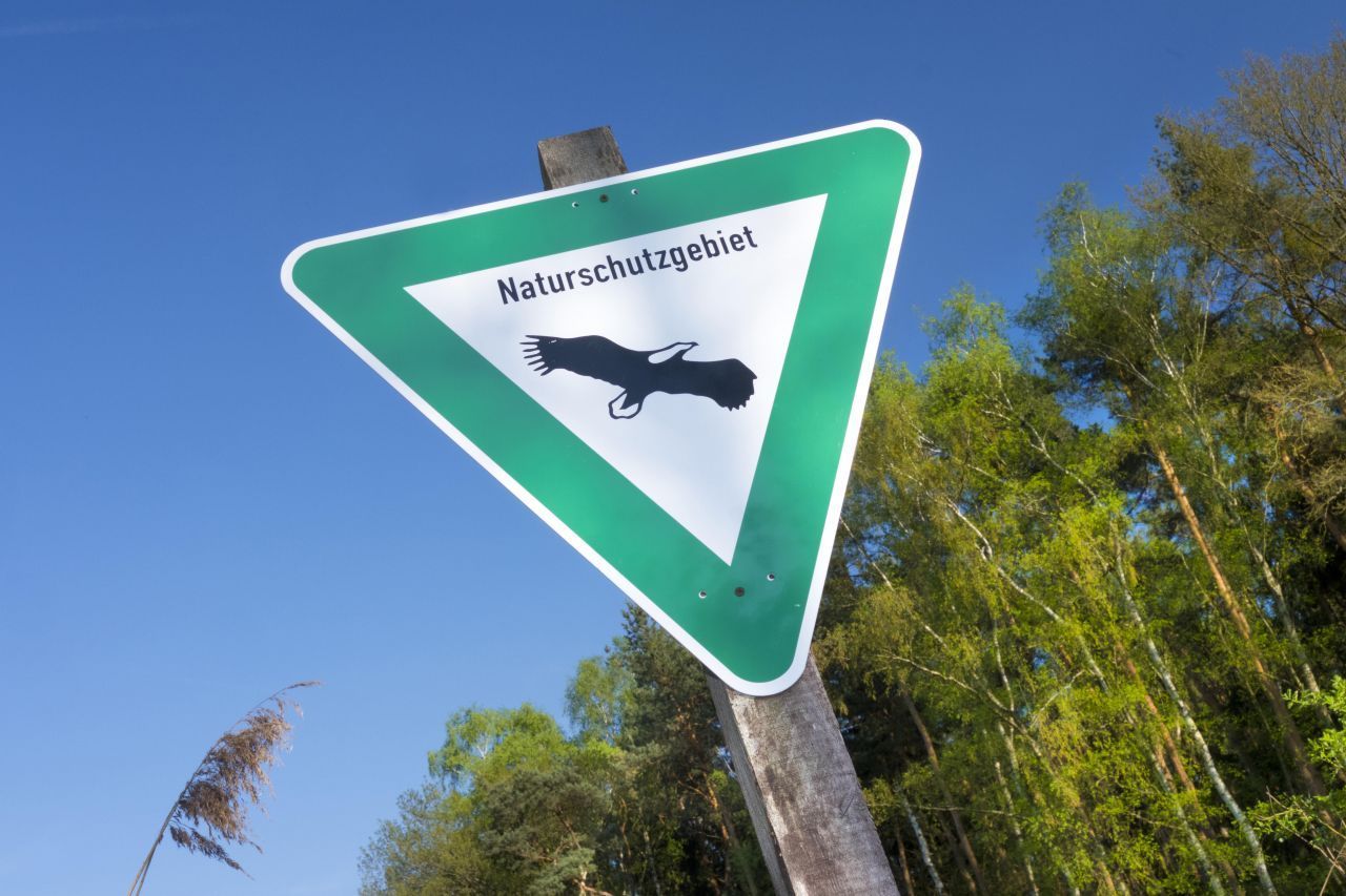 Erkennbar sind Naturschutzgebiete in Baden-Württemberg, Bayern, Hamburg, Hessen, Nordrhein-Westfalen, Rheinland-Pfalz und dem Saarland an einem grünen, dreieckigen Schild, auf dem ein Seeadler abgebildet ist.