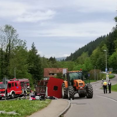 Einsatzkräfte stehen neben dem umgestürzten Maiwagen