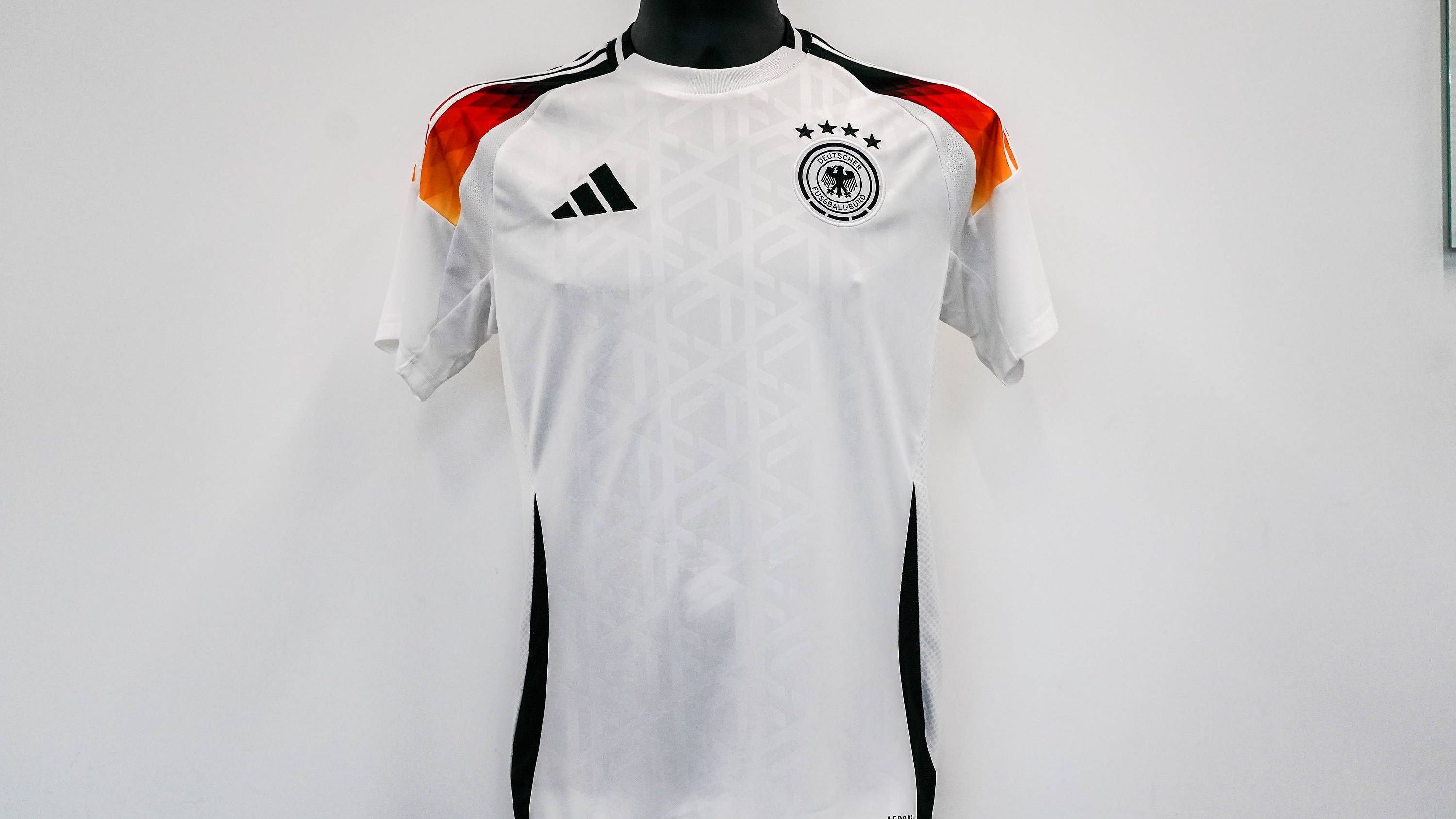 <strong>Gruppe A: Deutschland - Heimtrikot<br></strong>Das deutsche Heimtrikot ist überwiegend in Weiß gehalten, vom Hals zu den Ärmeln verlaufen die Farben der Nationalflagge.<br>Aber wie sehen die Jerseys der anderen Teams aus? Wer wagt noch Neues, wer setzt auf Altbewährtes? Antworten gibt's in der Galerie.