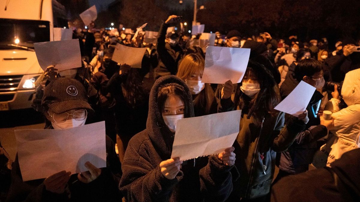 Demonstranten in Peking halten leere Papiere hoch, während sie protestieren.