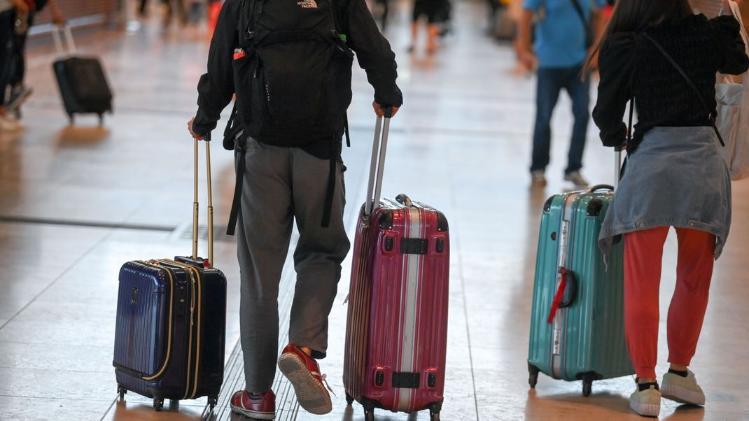 Reisende gehen im Flughafen Berlin-Brandenburg (BER) müssen mit Flugausfällen rechnen.