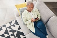 Woman, relax and typing with phone on sofa