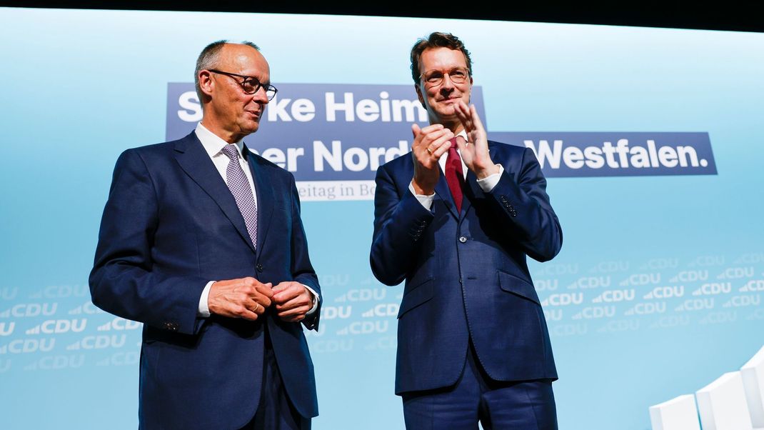 30. August 2025, Nordrhein-Westfalen, Bonn: Bundeskanzler Friedrich Merz (l, CDU) steht nach seiner Rede beim Landesparteitag der CDU Nordrhein-Westfalen mit Hendrik Wüst (CDU), Ministerpräsident von Nordrhein-Westfalen, auf der Bühne.