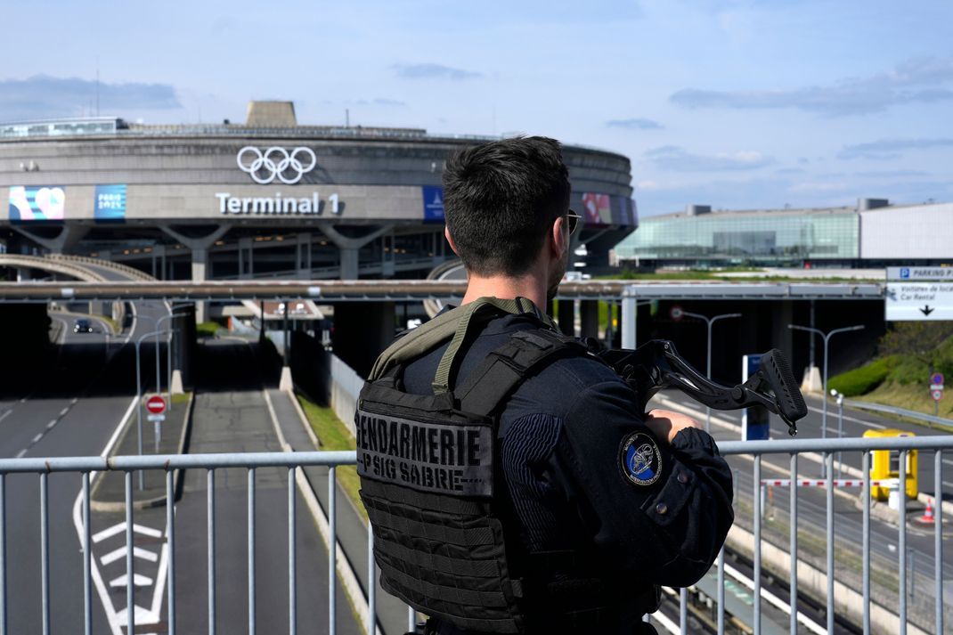 Ein Polizist patrouilliert vor dem Terminal 1 des Flughafens Charles de Gaulle in Paris, wo die olympischen Ringe installiert wurden.