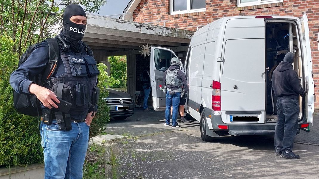 Im Einsatz gegen Schleuserkriminalität: Maskierte Beamte vor einem Wohnhaus während der Razzia.