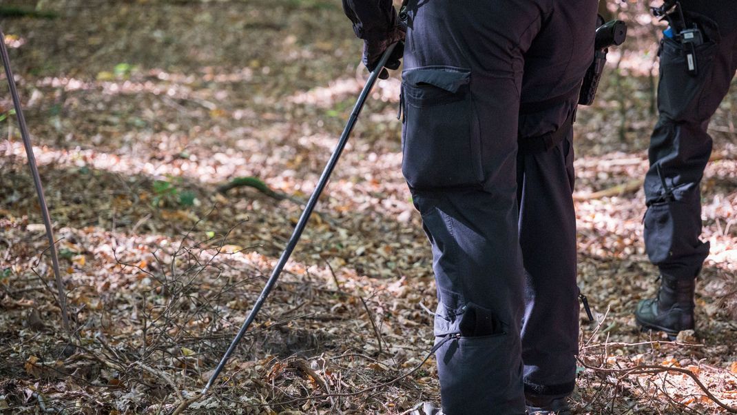 Symbolbild: Polizisten suchen den Waldboden nach einem Vermissten ab. 