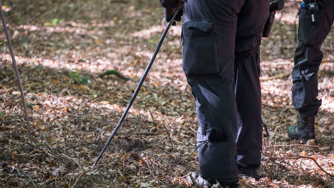 Symbolbild: Polizisten suchen den Waldboden nach einem Vermissten ab. 
