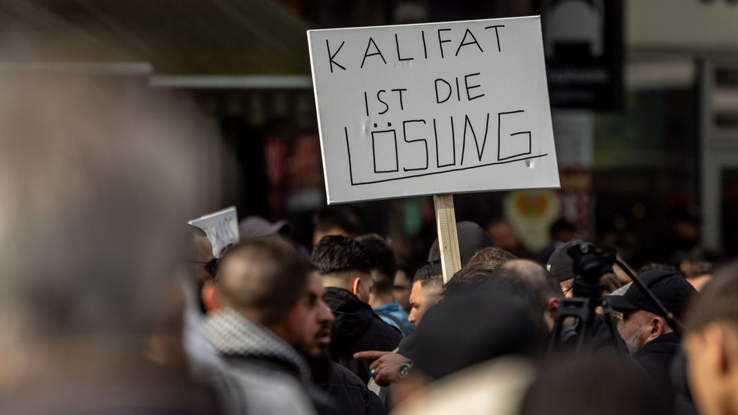 Teilnehmende einer islamistischen Demonstration postulieren auf einem Plakat das "Kalifat ist die Lösung". Auch Redner auf der Kundgebung rufen das Kalifat als Ziel aller islamischen Staaten aus. 