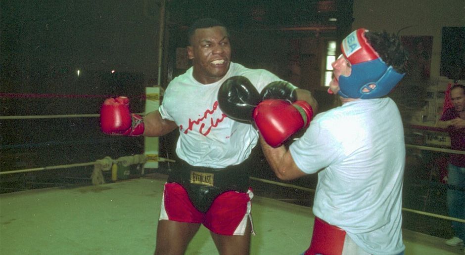 
                <strong>Mike Tyson</strong><br>
                D'Amato wurde Tysons väterlicher Freund und nahm den jungen Boxer bei sich zu Hause auf. Nachdem er den 13 Jahre alten Tyson erstmals beim Sparring gesehen hatte, soll der legendäre Box-Trainer prophezeit haben: "Das wird der künftige Weltmeister im Schwergewicht." In seinem Keller bildete D'Amato Tyson zu einem kommenden Profi-Boxer aus und brachte ihm den berühmten Peek-a-Boo-Stil bei.
              
