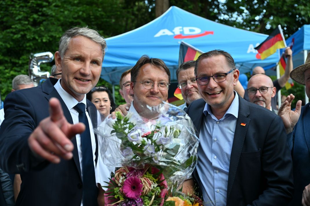 Björn Höcke  (l) , Vorsitzender der AfD Thüringen und Tino Chrupalla, AfD-Bundesvorsitzender (r) gratulieren dem Wahlsieger des Thüringer Kreis Sonneberg, Robert Sesselmann (AfD, M) im Garten eines Restaurant. 