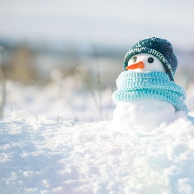 Little snowman in a cap and a scarf on snow in the winter. Christmas card with a lovely snowman, copy space