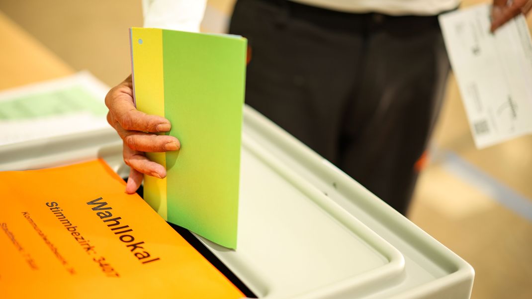 Ein Mann wirft seine Stimmzettel in eine Wahlurne. Am Sonntag finden in Nordrhein-Westfalen Kommunalwahlen statt.
