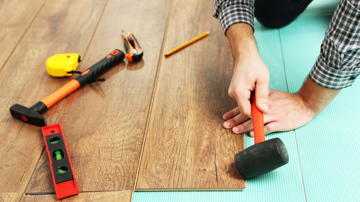 Carpenter worker installing laminate flooring in the room