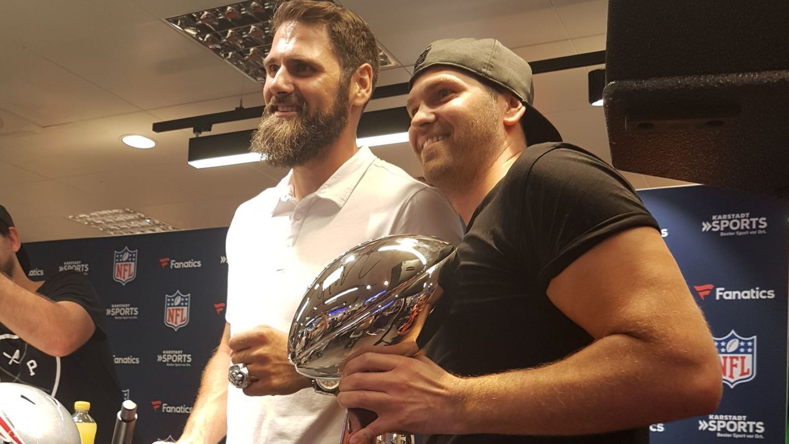 
                <strong>Deutsche NFL-Stars zur Autogramm-Stunde in München</strong><br>
                Vollmer spielte von 2009 bis 2016 als Offensive Tackle für die New England Patriots. Als Beschützer von Tom Brady gewann der heute 35-Jährige in der Saison 2014 und 2016 jeweils den Super Bowl. Ein Fan bringt sogar seine eigene Vince Lombardi Trophy mit. Vollmer präsentiert stolz den originalen Championship Ring.
              