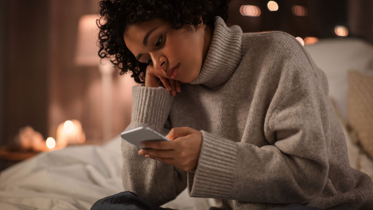 technology, internet, communication and people concept - woman with smartphone sitting in bed at home at night