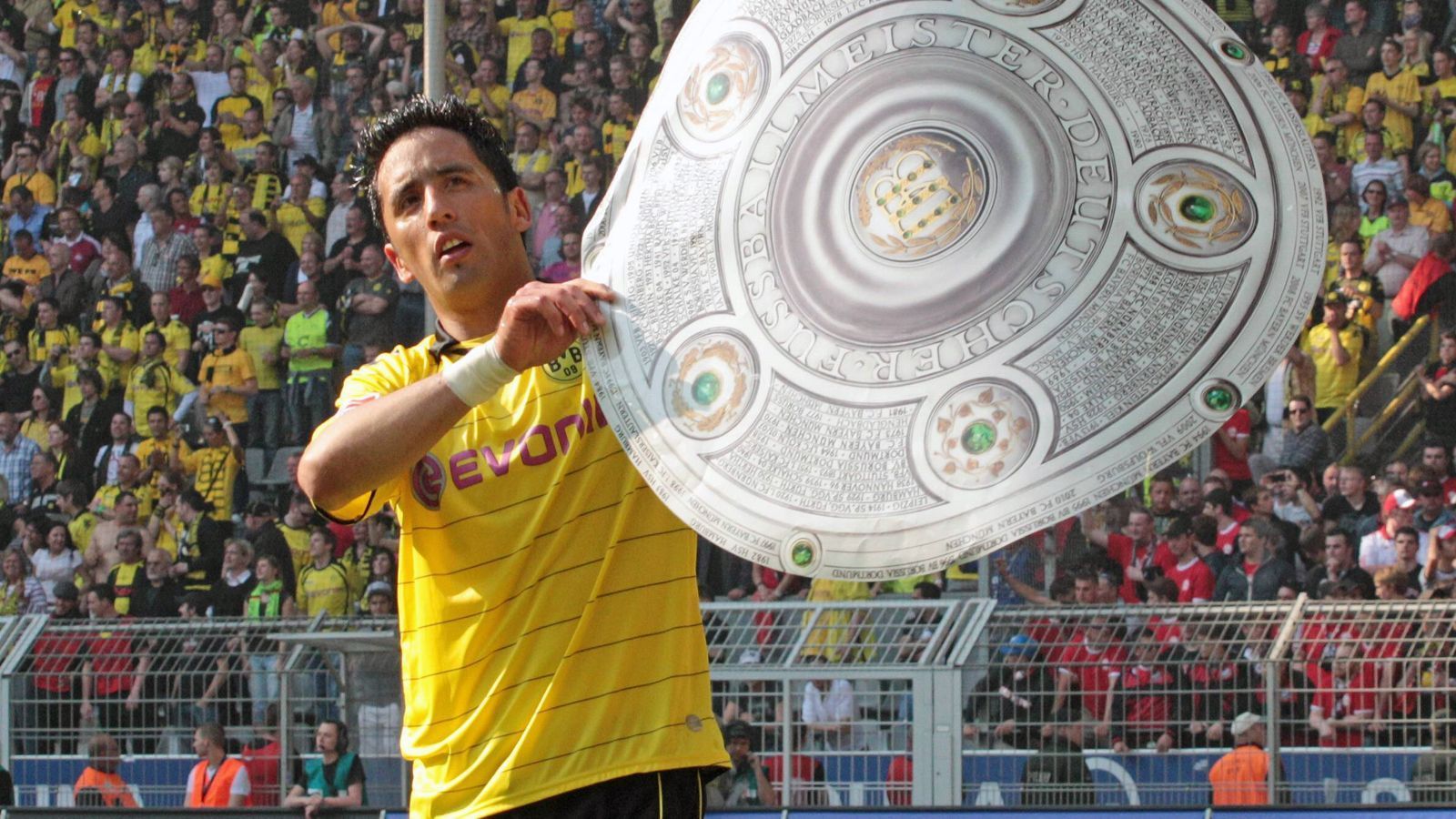 
                <strong>Lucas Barrios</strong><br>
                Mit 16 Treffern war Stürmer Lucas Barrios in der Meistersaison des BVB der mit Abstand beste Torjäger der Dortmunder und hatte damit massiven Anteil am Titelgewinn. Beim 2:0-Erfolg am 32. Spieltag gegen Nürnberg, der den vorzeitigen Titelgewinn besiegelte, brachte der Südamerikaner den BVB nach gut einer halben Stunde in Führung. In der darauffolgenden Spielzeit lief ihm dann Robert Lewandowski den Rang ab und Barrios wechselte nach nur noch vier Treffern in der Hinrunde Anfang 2012 nach China. Danach folgten für den Stürmer diverse Stationen in Russland, Frankreich, Brasilien und Argentinien. Heute steht der 36-Jährige beim argentinische Klub Club de Gimnasia y Esgrima La Plata unter Vertrag, spielte dort bis zu dessen Tod unter Trainer Diego Armando Maradona. 
              