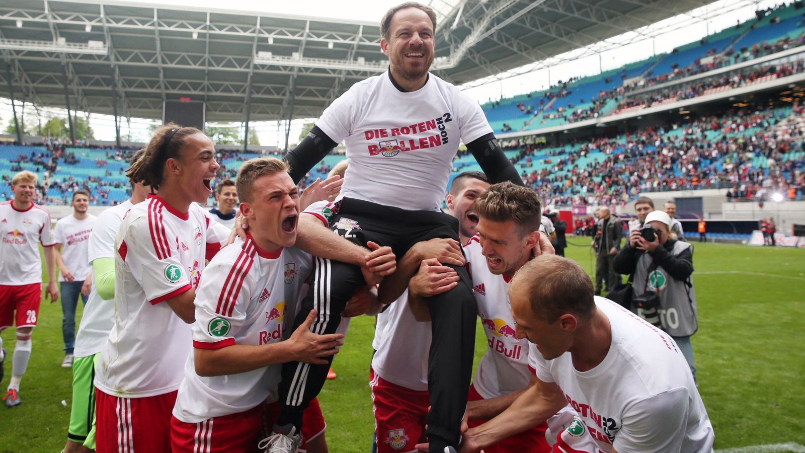 
                <strong>Saison 2013/14: 3. Liga</strong><br>
                In der 3. Liga wurde dann schon am Saisonstart erstmals die finanzielle Wucht der Leipziger offensichtlich, als sich der Drittliga-Aufsteiger verhältnismäßig extrem teure Talente wie Yussuf Poulsen (li.) oder Joshua Kimmich (2.v.l.) leistete. In der Winterpause schlugen die Sachsen wieder auf dem Transfermarkt zu, holten mit Federico Palacios (Wolfsburg) ein hochveranlagtes Offensivtalent für kolportierte 600.000 Euro Ablöse. Sportlich war das Projekt RB Leipzig in der 3. Liga dann nach den hohen Investitionen früh auf Kurs, der Aufsteiger stand vom 15. Spieltag weg durchgehend auf einem direkten Aufstiegsplatz in Richtung 2. Bundesliga. Am Ende stieg die Zorniger-Elf nach einem 5:1-Sieg gegen Saarbrücken bereits vorzeitig (am 37. Spieltag) auf - der nächste Meilenstein in der rasanten Leipziger Entwicklung!
              