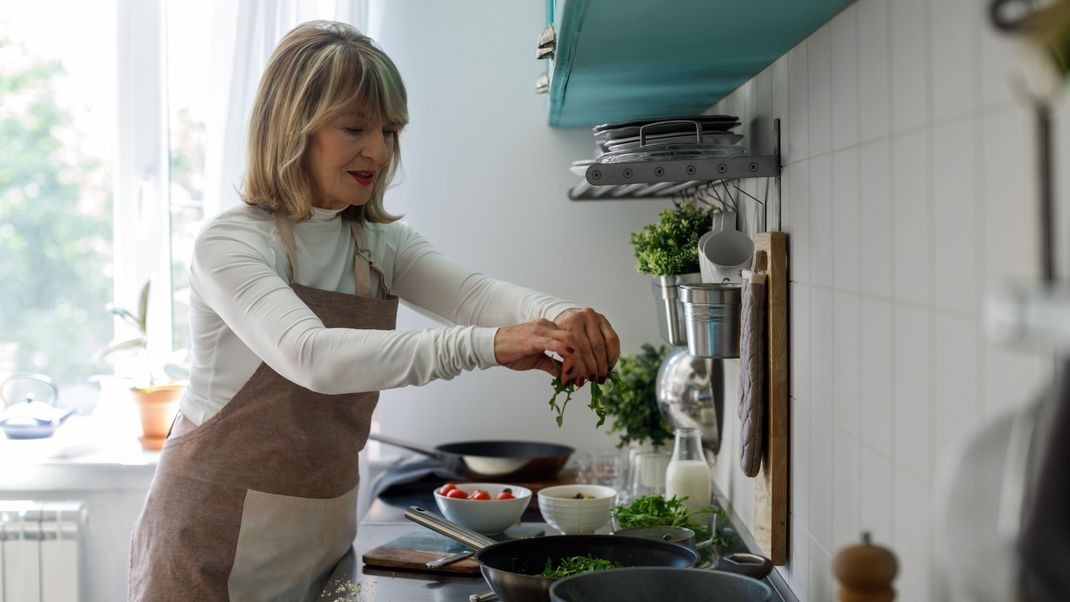 Pretty senior Caucasian woman cooking at home.