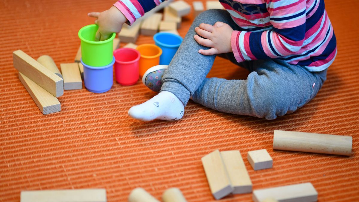 Ein Mädchen spielt in einer Kita mit bunten Bechern und Bauklötzen.