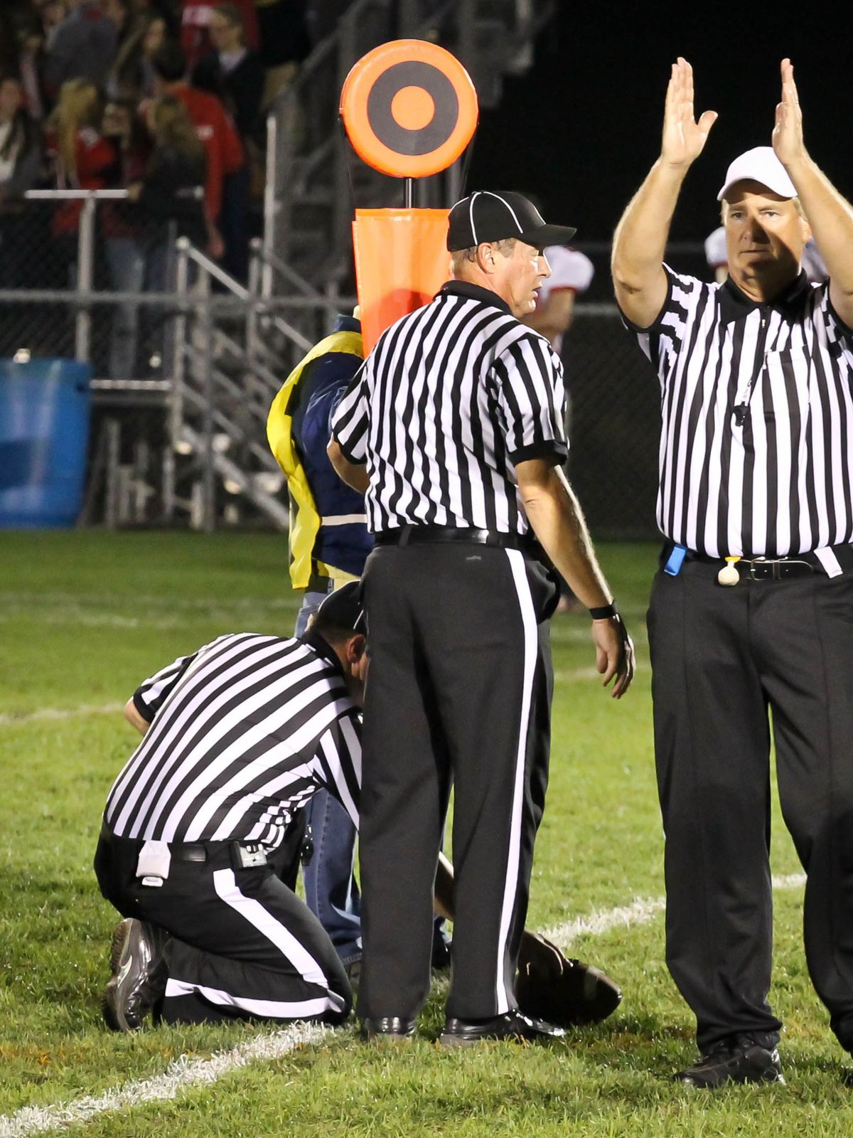 Football Referees Gesturing Fourth Down and Short, Referees with chain gang measuring yardage, indicating that its fourth down and short.