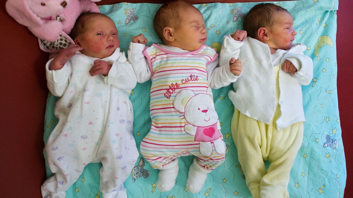 Drei Säuglinge liegen nebeneinander auf einer Kuscheldecke.