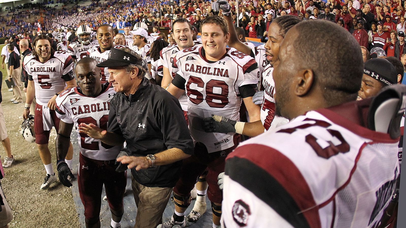 
                <strong>Steve Spurriers "Swamp-Revenge"</strong><br>
                Der legendäre Head Coach Steve Spurrier, nach dem auch das Footballstadion der Gators benannt ist, trainierte zum Ende seiner Karriere die South Carolina Gamecocks. Diese konnten bis zum Jahr 2010 kein einziges ihrer zwölf Spiele in der Programmhistorie in Florida bei den Gators gewinnen.Wie kann es da anders sein, als dass genau in dieser Saison 2010 Spurrier mit den Gamecocks in den "Swamp" einzieht und sich mit einem 36:14-Sieg die Teilnahme am SEC Championship Game sichert. Das jedoch ging gegen Auburn mit einem gewissen Cam Newton auf der Quarterback-Position verloren. Newton war im Übrigen auch mal ein Florida Gator und Back-Up für Tim Tebow, bevor er nach Auburn transferiert wurde. Apropros Tebow ...
              