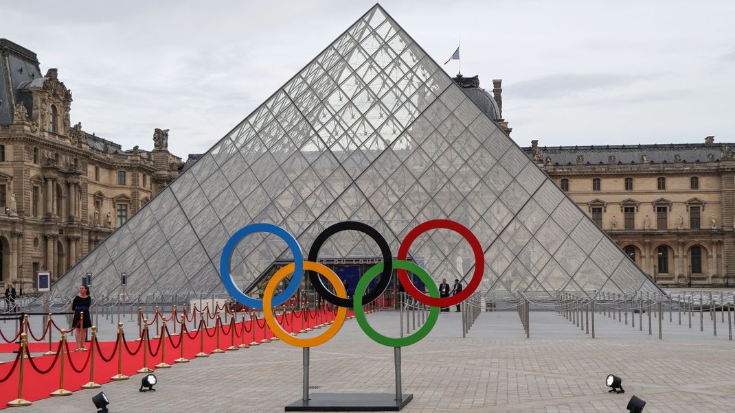 Vor dem Louvre in Paris sind die Olympischen Ringe aufgebaut.