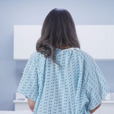 Rear view of female patient standing indoors medical clinic