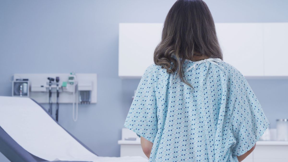 Rear view of female patient standing indoors medical clinic