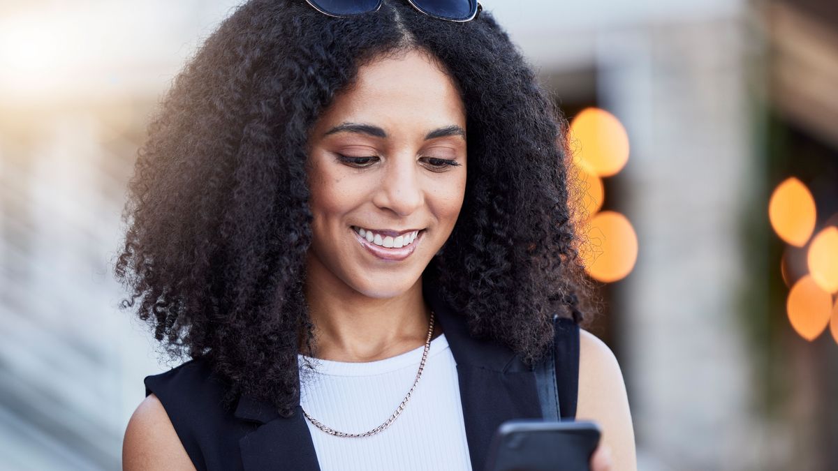 Frau lächelt und schaut auf ihr Handy