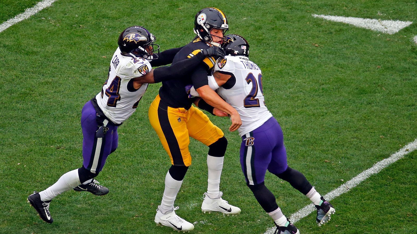 
                <strong>23. Duell: Ravens gewinnen schmutzig</strong><br>
                Wie groß die Rivalität zwischen den Ravens und Steelers ist, erfährt Quarterback Mason Rudolph (Mitte). Der Ersatz für den verletzten Roethlisberger muss nach einem üblen Hit von Earl Thomas (rechts) das Feld verlassen. Die Ravens gewinnen trotz dreier Interceptions von Lamar Jackson mit 23:20 nach Verlängerung. Es ist das 16. Mal, dass das Spiel mit vier Punkten oder weniger entschieden wird. Harbaugh führt 12:11
              