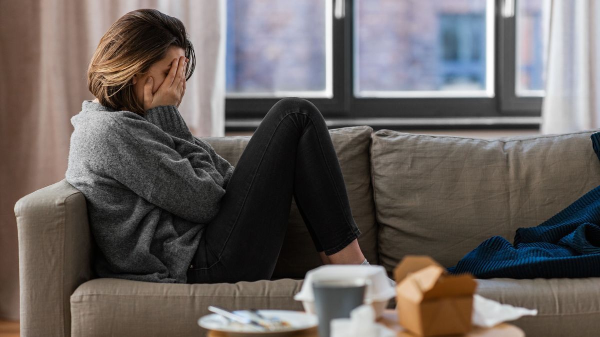 stressed woman sitting on sofa at home