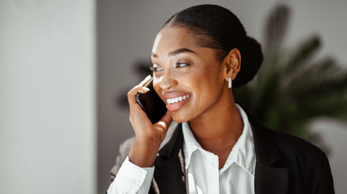 Closeup portrait of black businesswoman talking on phone in office, enjoying business conversation, having pleasant call