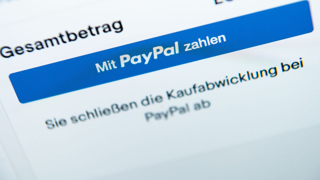 Der Schriftzug "Mit PayPal zahlen" steht auf einem Laptop-Bildschirm.